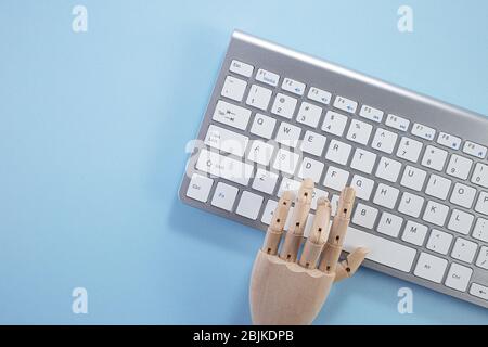 Tastiera del laptop su sfondo blu, stile minimalista. Spazio di lavoro con una mano di legno, laptop. Scrivania di stile minimalista e moderno. Disposizione piatta Foto Stock