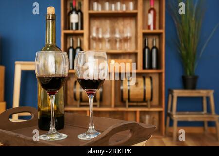 Due bicchieri e una bottiglia di vino su vassoio di legno all'interno Foto Stock