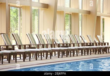 Chaise longue vicino alla piscina in un hotel di lusso Foto Stock