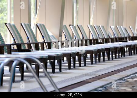 Chaise longue vicino alla piscina in un hotel di lusso Foto Stock