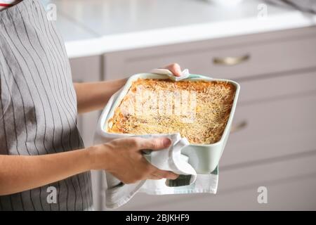 Donna che mantiene la griglia da forno con spinaci lasagne in cucina Foto Stock