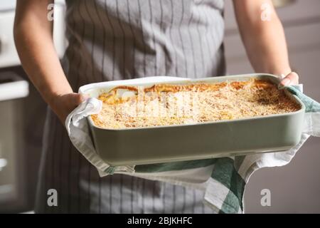 Donna che mantiene la griglia da forno con spinaci lasagne in cucina Foto Stock