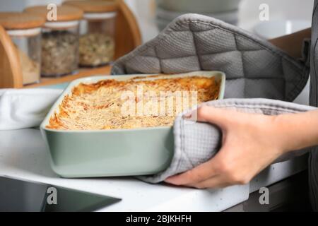 Donna che mantiene la griglia da forno con spinaci lasagne in cucina Foto Stock