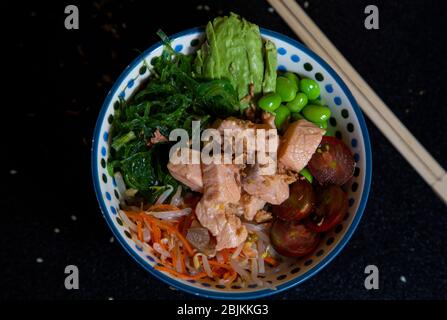 ciotola di salmone fatto in casa (avocado, salmone, wakame, edamame, pomodoro ciliegia e riso), vista dall'alto. Poke. Foto Stock