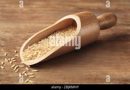 Cucchiaio di riso marrone su fondo di legno Foto Stock