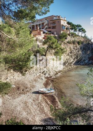 Punto roccioso con ville private sopra il mare azzurro calmo sull'isola delle Baleari. Foto Stock