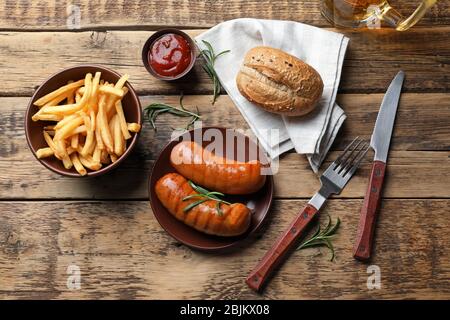 Piatto con deliziose salsicce alla griglia su sfondo di legno Foto Stock