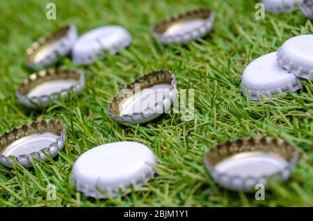 Pile di bottiglie di birra scartate su erba Foto Stock