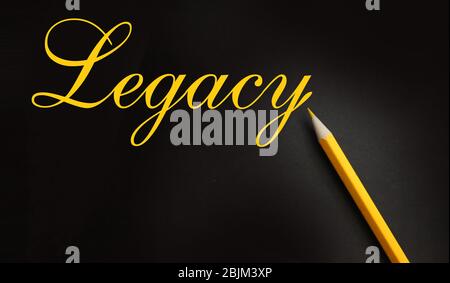 Parola legacy, scritta con matita color pastello giallo su carta nera. Eredità immobiliare ultimo concetto Foto Stock