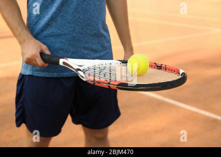 Uomo con racchetta da tennis e palla in piedi sul campo Foto Stock