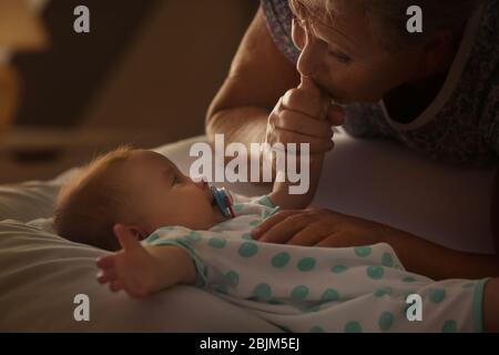 Donna anziana baciando la mano del suo piccolo nipote a casa Foto Stock