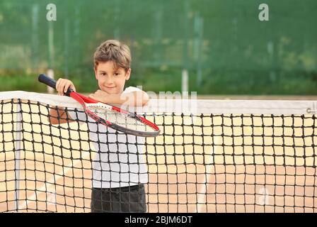 Carino ragazzo con racchetta da tennis sul campo Foto Stock