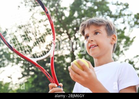 Carino ragazzino che gioca a tennis sul campo Foto Stock