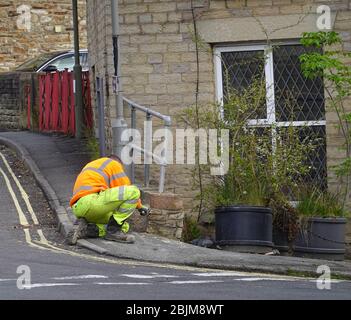 Un operaio ripara un muro di bassa e ringhiere danneggiati all'angolo di Mellor Road e Bridge Street a New Mills, Derbyshire. Foto Stock