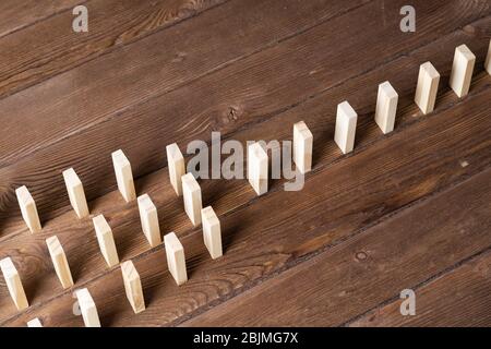 File di domino in piedi su tavolo di legno Foto Stock