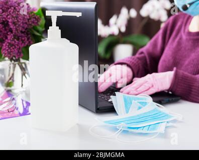 Gel igienizzante per l'igiene delle mani, protezione da corona di coronavirus Covid-19, maschere chirurgiche per il viso blu. Donna che indossa maschera, guanti di lavoro Foto Stock