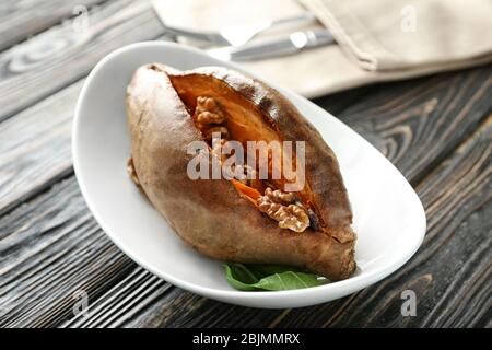 Piatto con patate dolci cotte su tavolo di legno Foto Stock