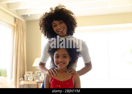 Donna gara mista con la sua figlia giovane sorridente alla macchina fotografica Foto Stock