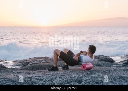 Uomo che fa auto massaggio del corpo con un rotolo. Formazione fascia Foto Stock