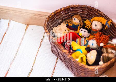Bambole fatte a mano e personaggi di peluche in cesto su tappeto di straccio Foto Stock