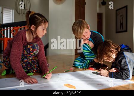 Tre bambini che lavorano a casa per un progetto artistico Foto Stock