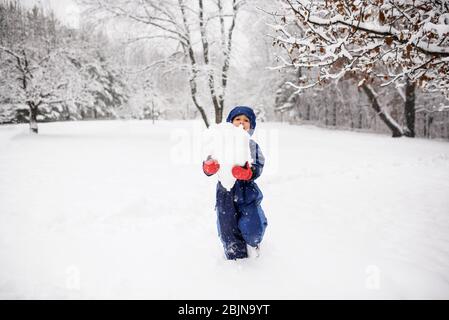 Ragazzo che porta una palla da neve gigante per fare un pupazzo di neve, USA Foto Stock