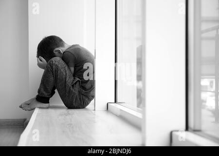 Ragazzino seduto sul davanzale. Concetto di violenza domestica Foto Stock