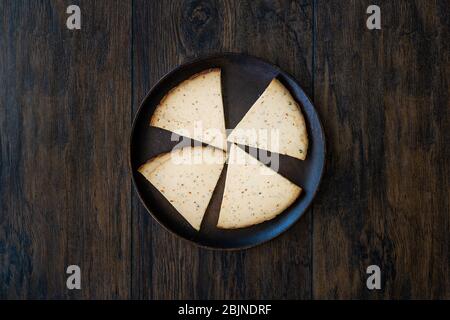 Fette di formaggio affumicato piccante Circassiano Triangle su piatto di legno scuro con spezie. Pronto a mangiare. Foto Stock