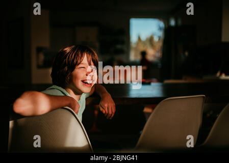 Ragazzo felice seduto al tavolo della sala da pranzo Foto Stock