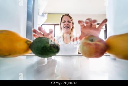 Giovane donna in cucina scelta di frutta biologica per fare il succo estratto fresco - ragazza felice che si diverte a casa preparare un'insalata - cibo Helathy a Foto Stock