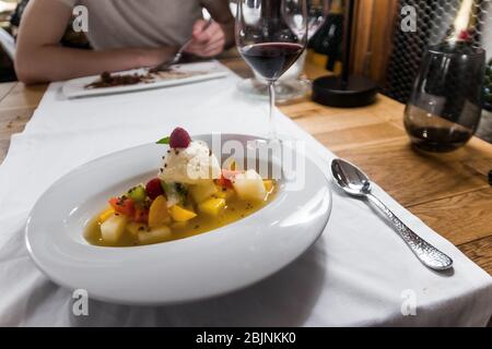 Delizioso dessert in un ristorante, Valencia, Spagna. Cibo gastronomico, bella presentazione. Frutta fresca di stagione e gelato con coulis di mango. Foto Stock