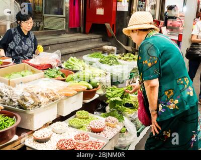 Seoul, Corea del Sud - 26 giugno 2017: La donna anziana acquista il verde al mercato di Gwangjang a Seoul. Foto Stock