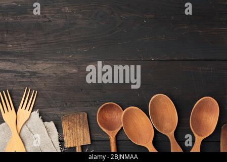 cucchiai di legno vuoti, forchette e spatole su uno sfondo di legno marrone da assi, vista dall'alto, sfondo cucina Foto Stock