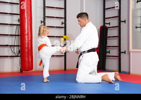 Istruttore di karate maschile formazione bambino piccolo in dojo Foto Stock