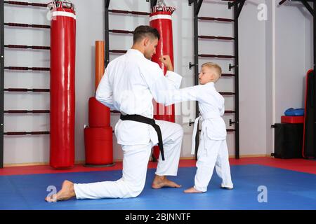 Istruttore di karate maschile formazione bambino piccolo in dojo Foto Stock