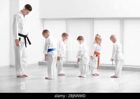 Bambini piccoli e istruttore che eseguono un arco rituale prima di praticare il karate nel dojo Foto Stock