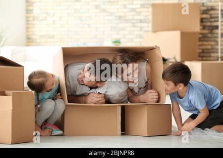 Genitori che giocano con i bambini mentre disimballano le cose in nuovo appartamento Foto Stock