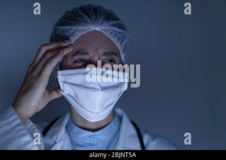 Operatore sanitario con cefalea che indossa maschera facciale durante la pandemia di coronavirus Covid19 Foto Stock