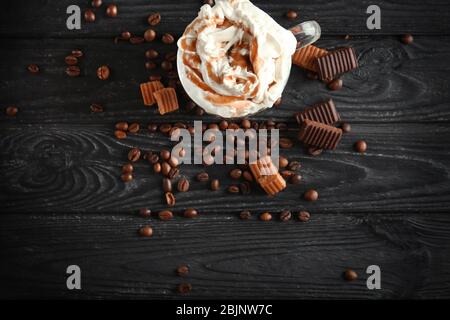 Bicchiere con caramello macchiato su fondo in legno Foto Stock