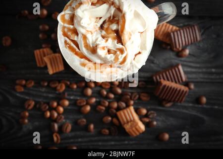 Bicchiere con caramello macchiato su fondo in legno Foto Stock