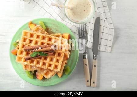 Piatto con deliziosi waffle alla cannella sul tavolo Foto Stock