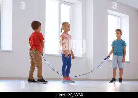 Adorabili bambini saltano la corda in interni Foto Stock
