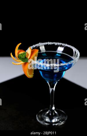 Decorazione per un cocktail di arancia e menta. Presentazione elegante e originale. Martini Blue Curacao su sfondo nero Foto Stock