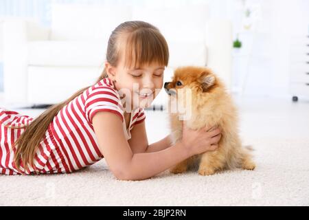 Ragazza carina con piccolo cane a terra a casa Foto Stock