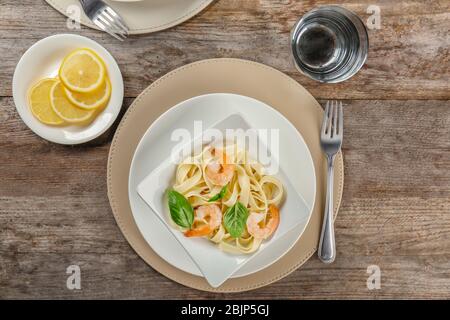 Piatto di pasta gustosa con gamberi su tavolo in legno, vista dall'alto Foto Stock