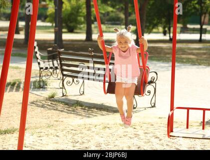 Adorabile bambina in altalena al parco giochi Foto Stock