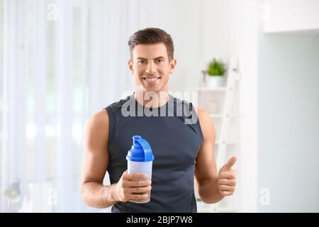 Giovane Azienda bottiglia con protein shake al chiuso Foto Stock