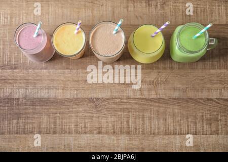 Diversi milkshake in vetreria su sfondo di legno Foto Stock