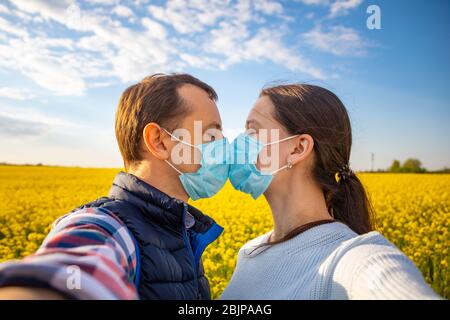 Coppia nell'amore, uomo e donna si baciano in maschera medica protettiva sul viso Foto Stock