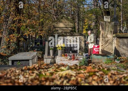 Una donna prega in una tomba nel cimitero di Rakowicki a Cracovia, Polonia 2019. Foto Stock